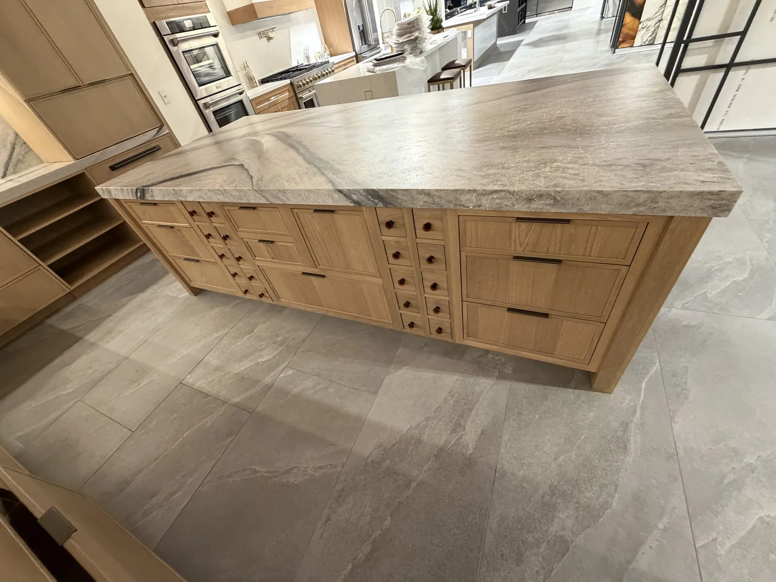 Island detail — White Oak Yosemite Brown base with Shiloh Square Beaded Inset doors, leather knob hardware, and soft-veined quartzite waterfall countertop