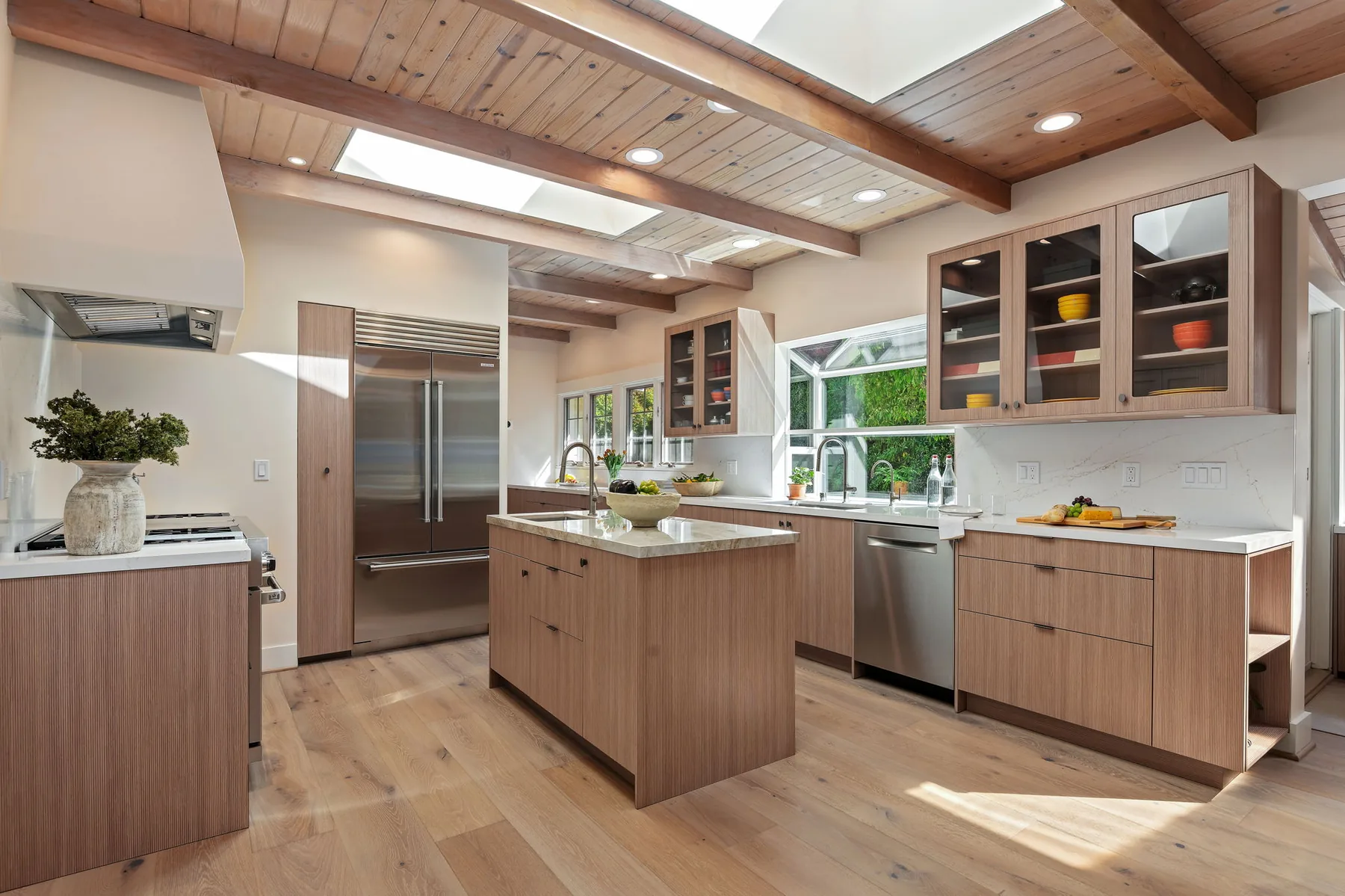 Kitchen overview with beamed ceiling, skylights, island, and full cabinetry program