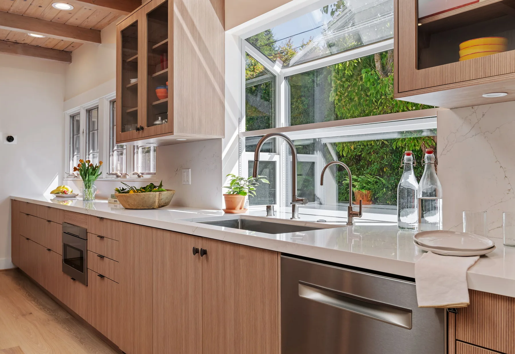 Sink detail with bridge faucet and water filter, garden window behind