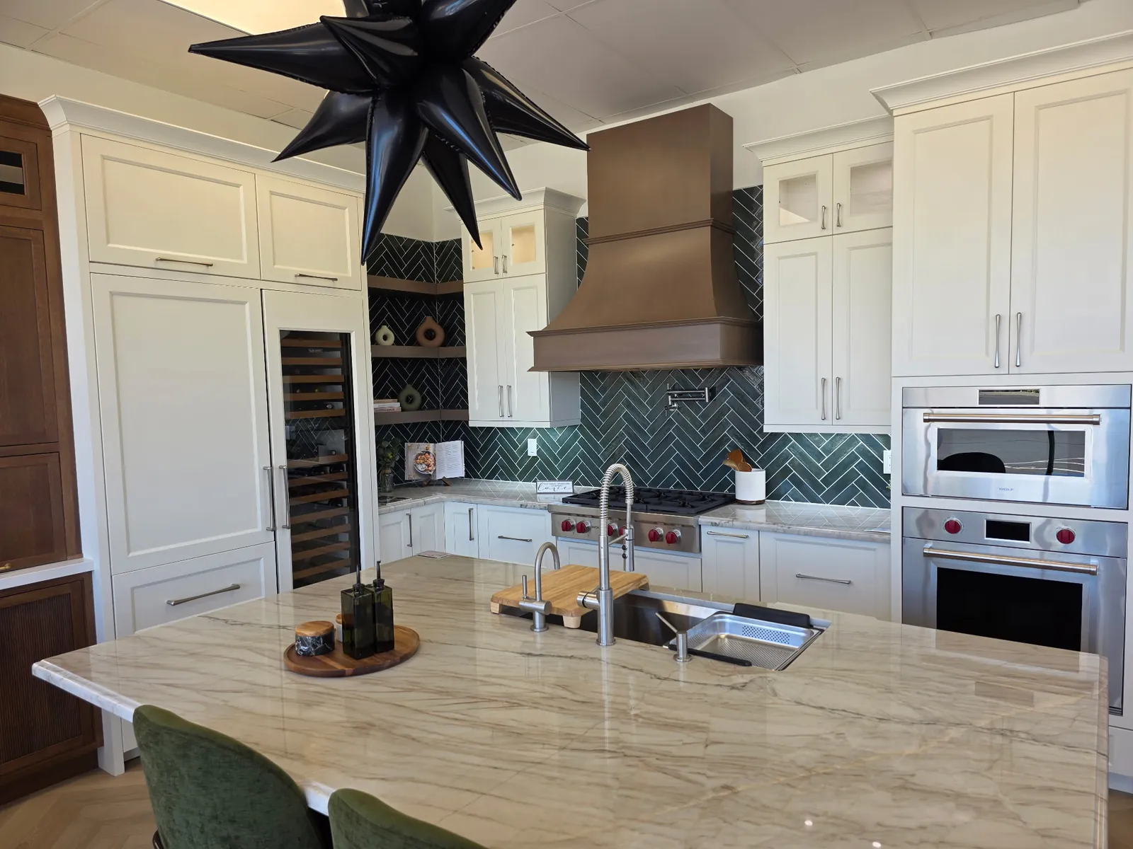 Wolf Renovations Shiloh Statesville kitchen in Shoji White — copper-bronze hood, deep green herringbone backsplash, panel-ready Sub-Zero column, marble waterfall island, and a Wolf range