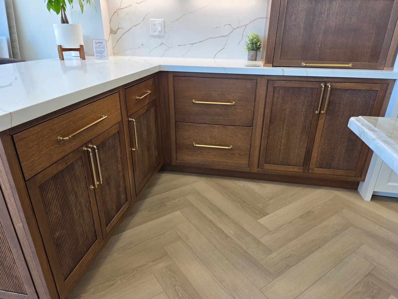 Detail of the Malibu Reeded door style in Quarter Sawn White Oak Braun — antique-brass bar pulls, herringbone wood floor
