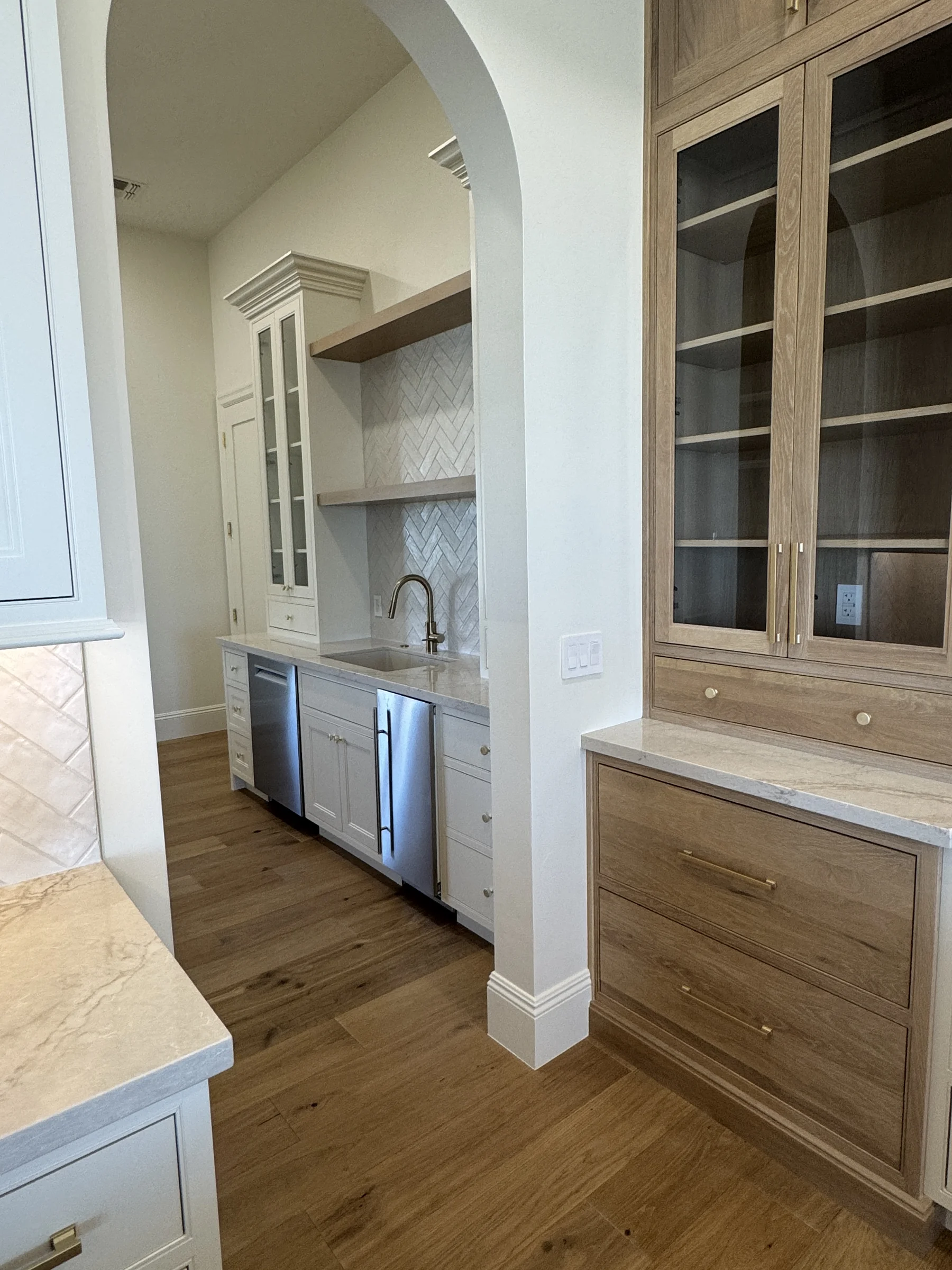 Silverstone Queen Creek butler's pantry — arched opening with herringbone tile and white oak display hutch alongside