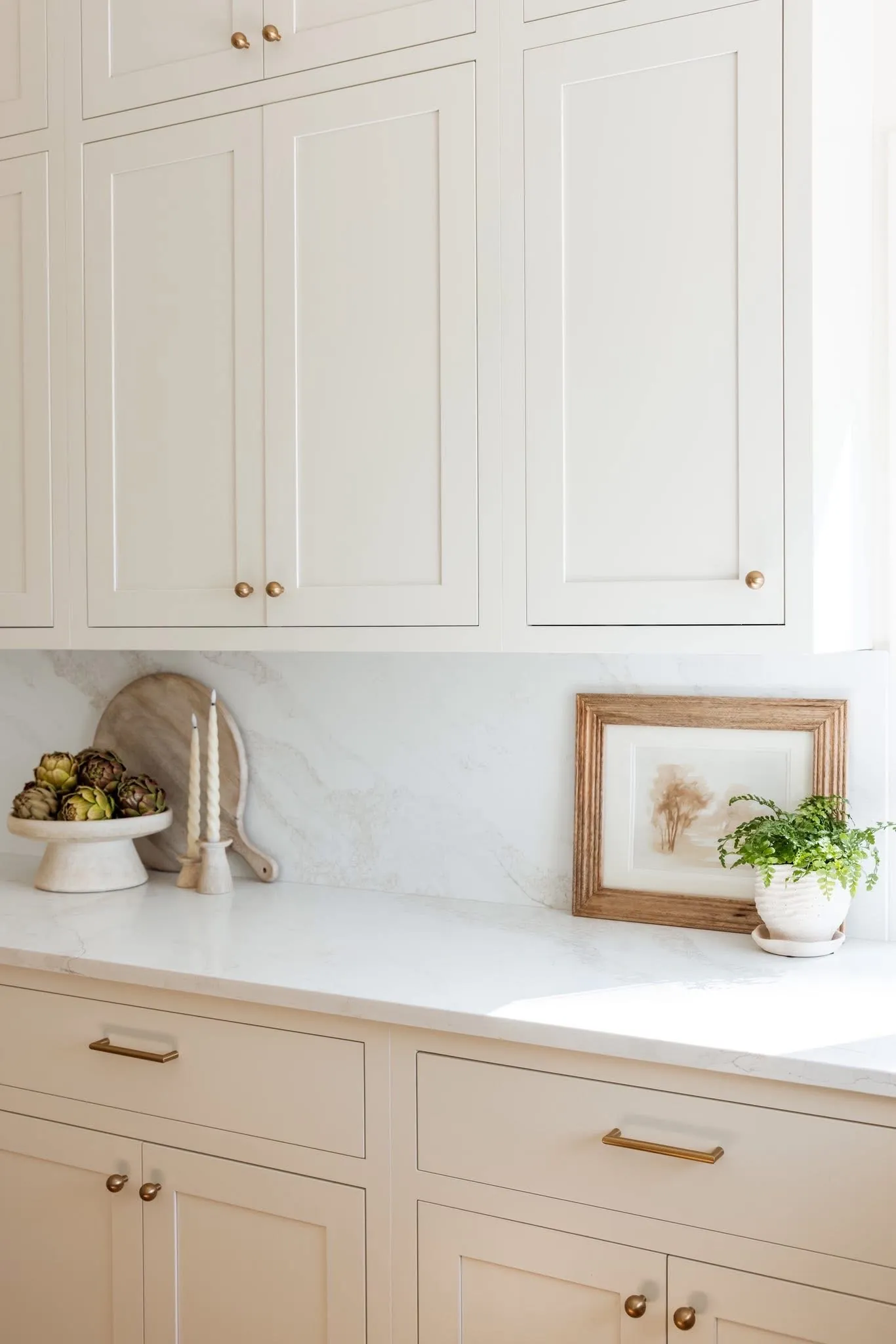 Stutler Cabinets Hanover kitchen — straight-on view of the white oak island with vase of branches and the Soft White perimeter behind