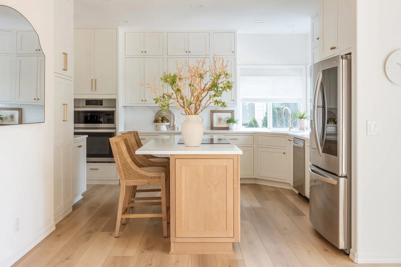 Stutler Cabinets Hanover kitchen — Soft White Hanover uppers with brass knobs over a marble counter, framed art and fern detail