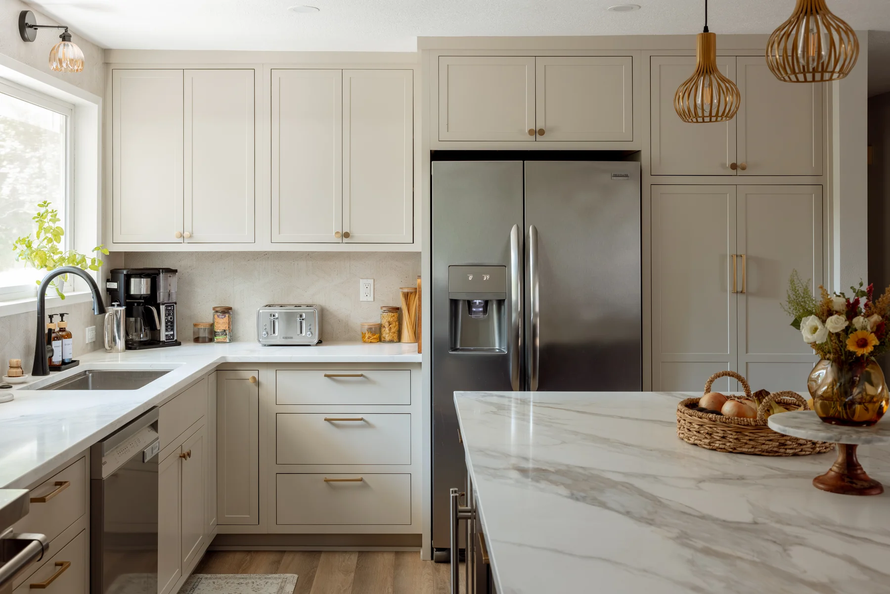 Stutler Cabinets kitchen — overall view with painted Shaker perimeter, marble island, and stainless side-by-side fridge