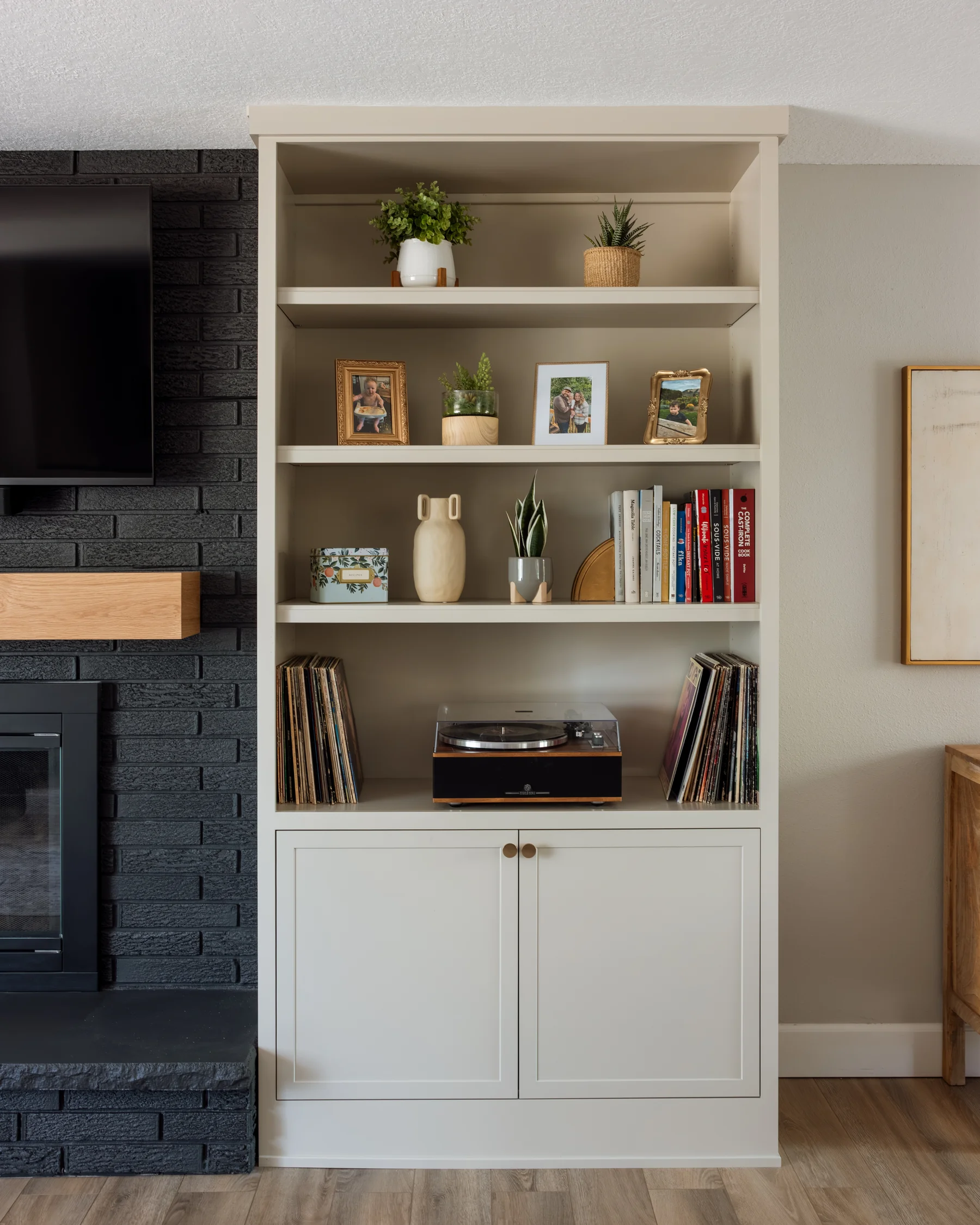 Stutler Cabinets living room — built-in shelving detail with turntable, vinyl, family frames, and base cabinet below